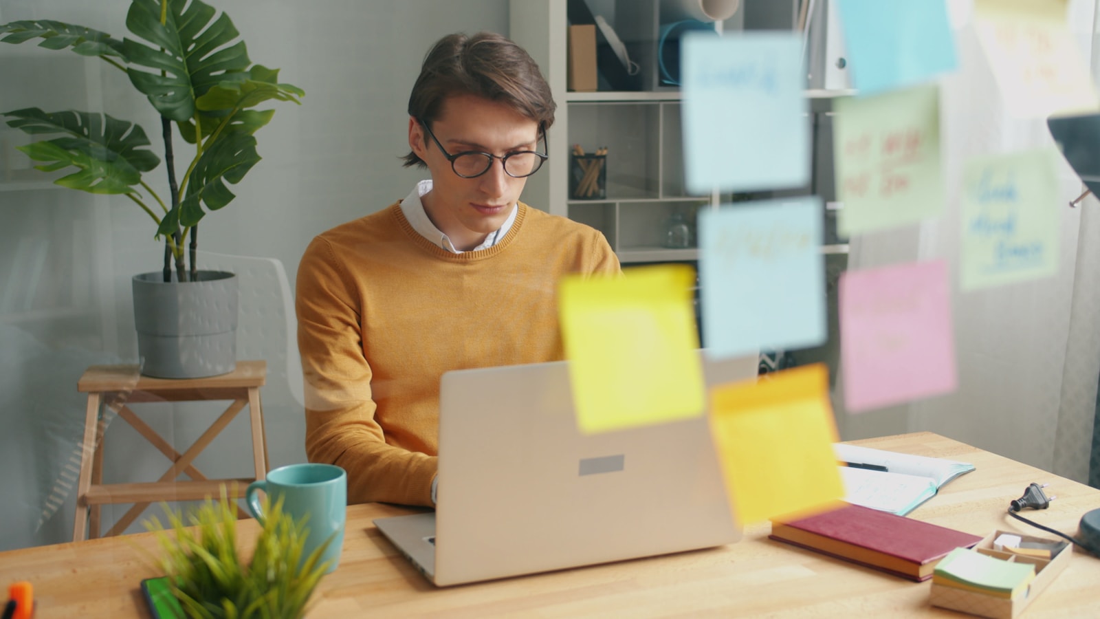 A designer working on a laptop behind a wall of colorful strategy notes